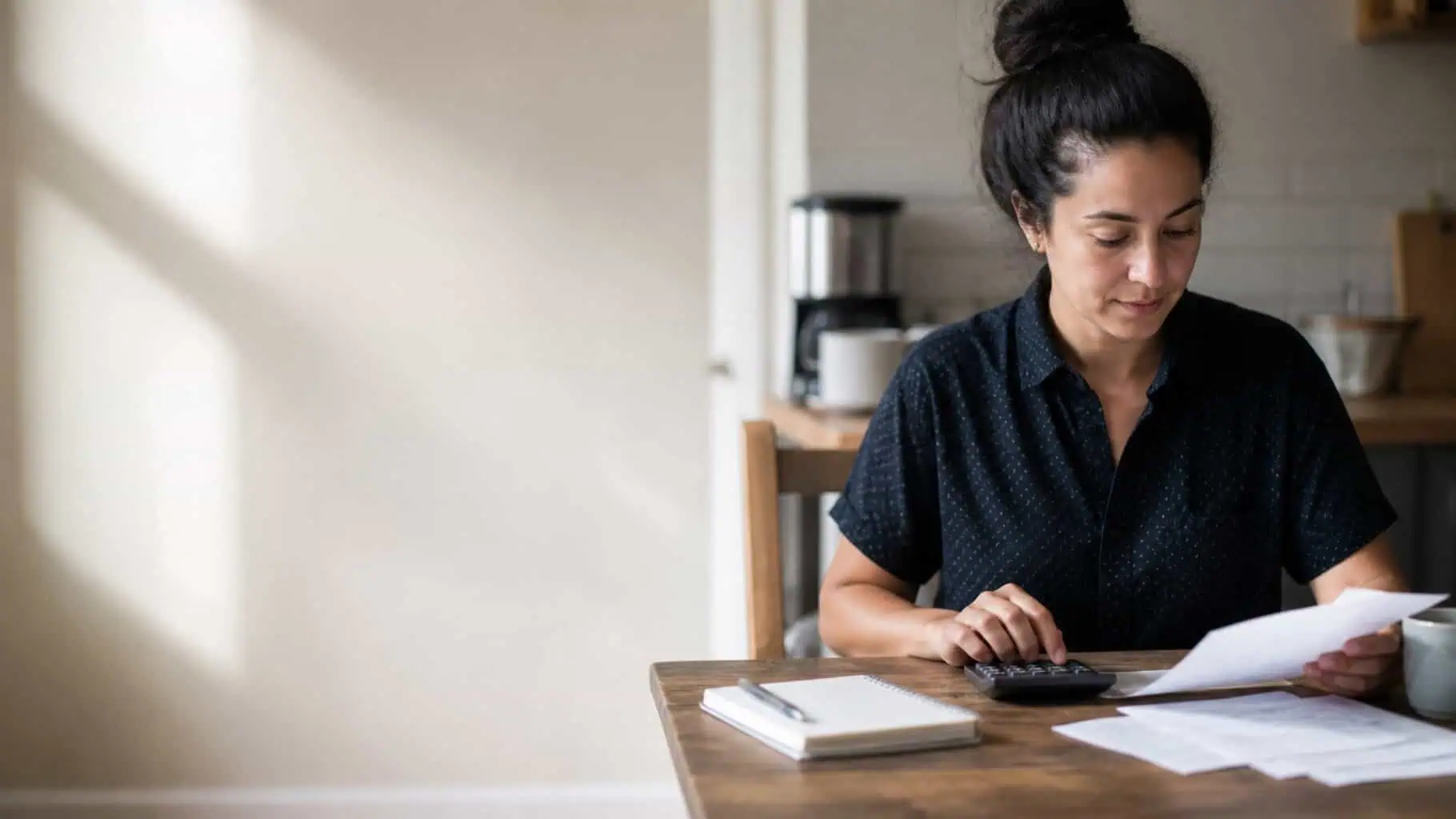 A business owner working through marketing costs with a calculator and invoices