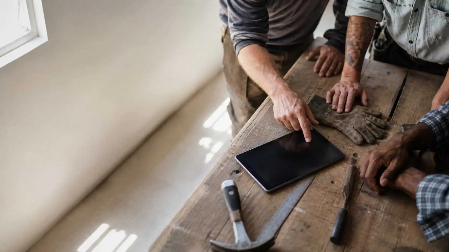 Tools and a tablet laid out on a workbench, representing the trades we serve